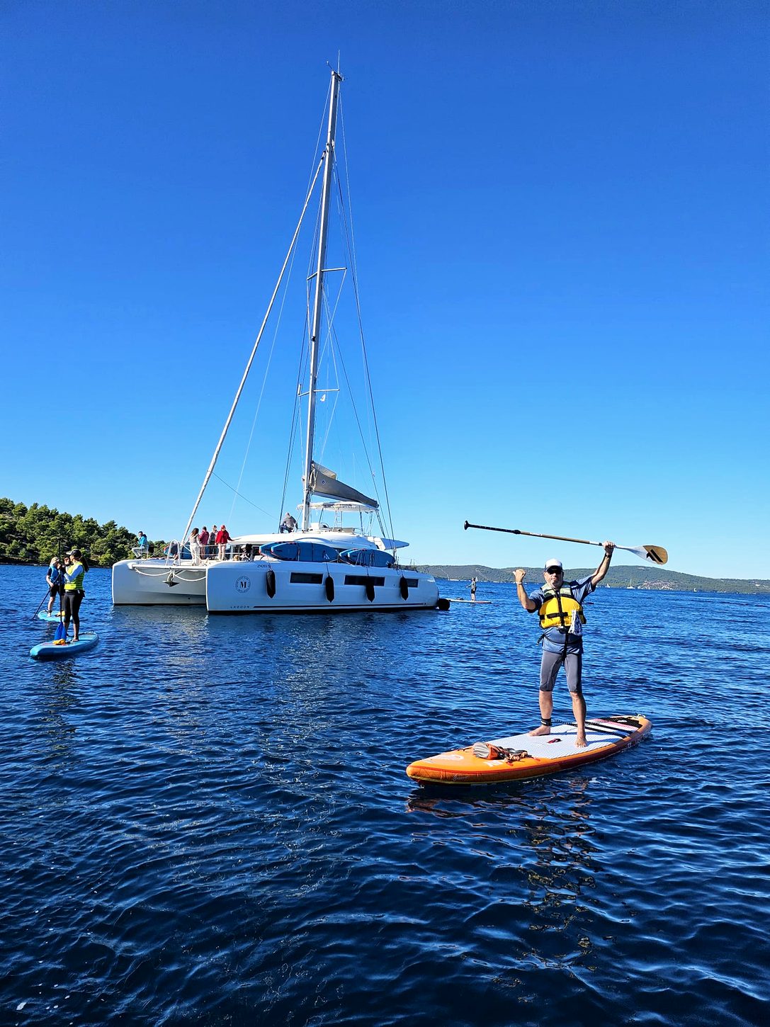 Katamaran vor der kroatischen Küste mit einem SUP-Board im Vordergrund
