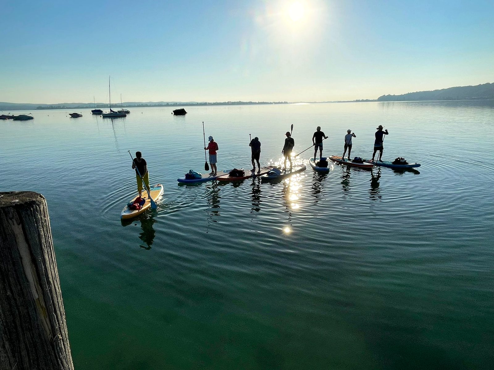 Gruppe von Paddlern im goldenen Morgenlicht auf spiegelglattem Wasser