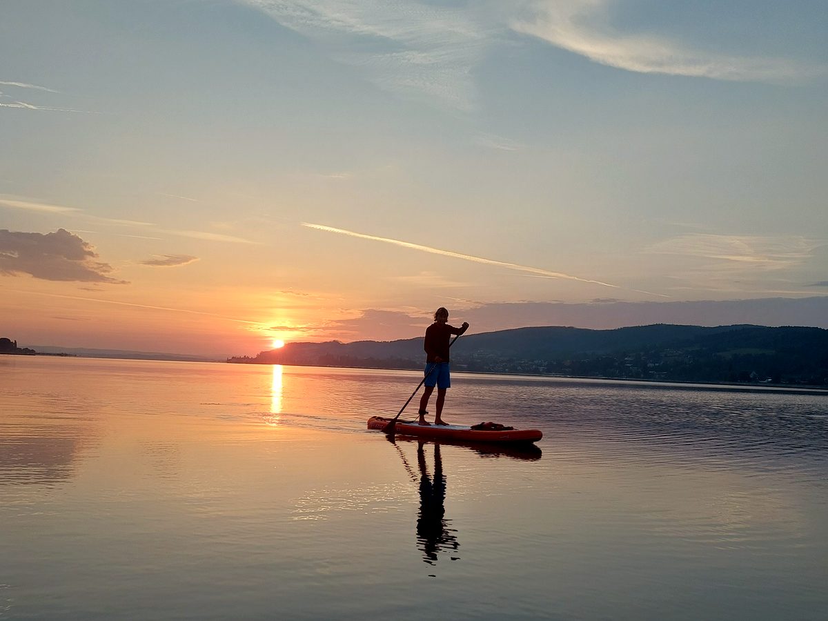Einzelner Paddler in der Abendsonne auf spiegelglattem Wasser