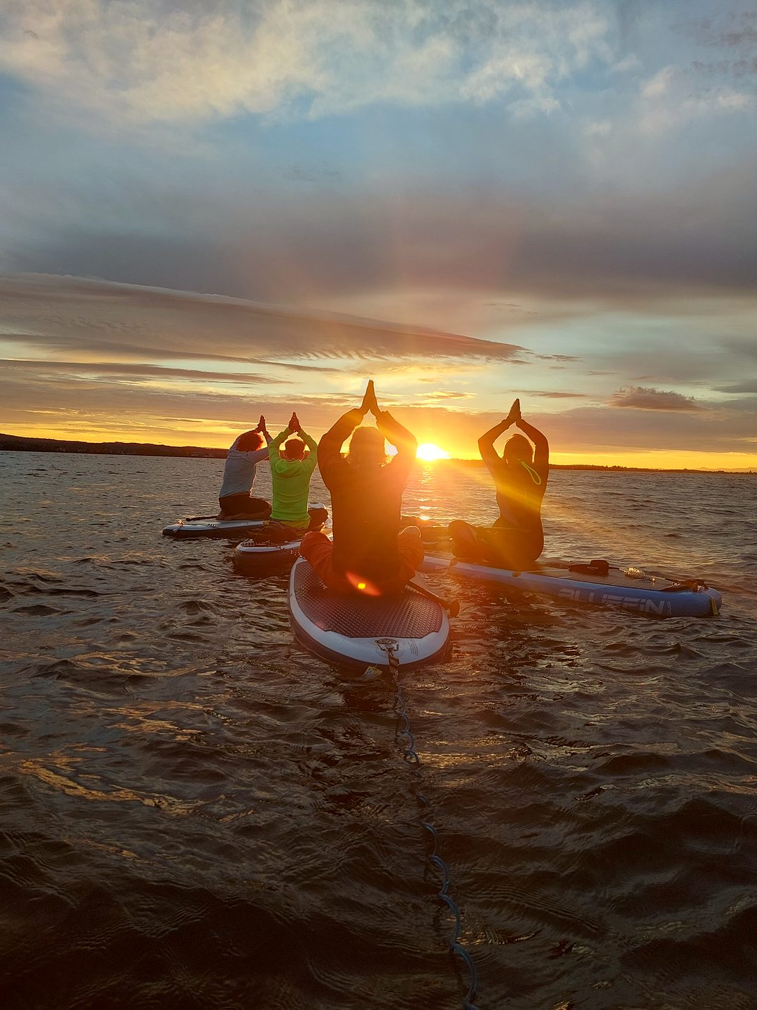 Yoga-Pose auf einem SUP-Board vor dem Sonnenuntergang über dem Untersee